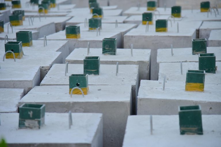 Close-up of concrete foundation blocks with embedded metal rods, ready for construction.