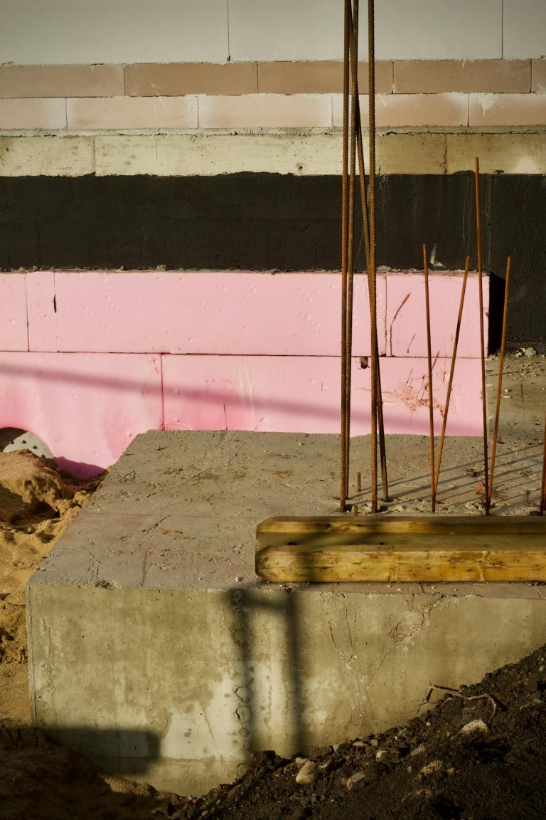 Close-up view of a construction site showing concrete and rebar against a pink and black backdrop.