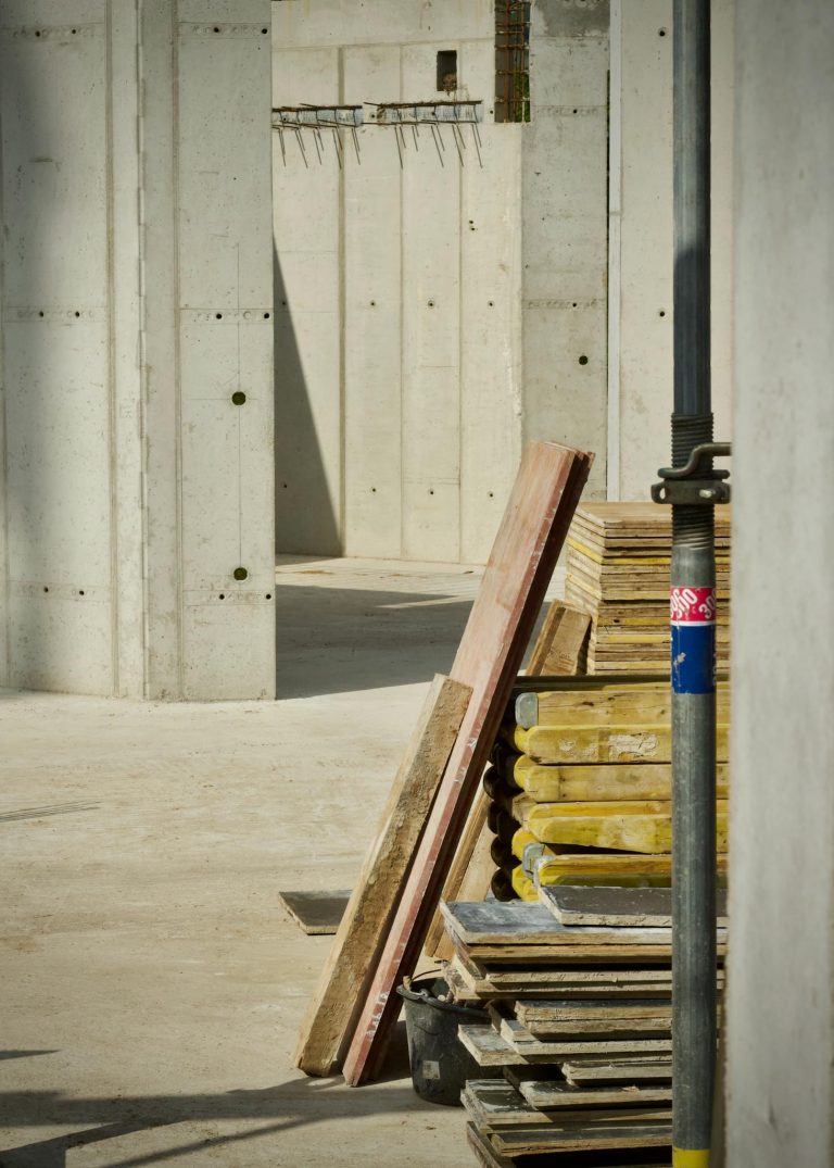 Concrete industrial site with stacked building materials and structure in progress.