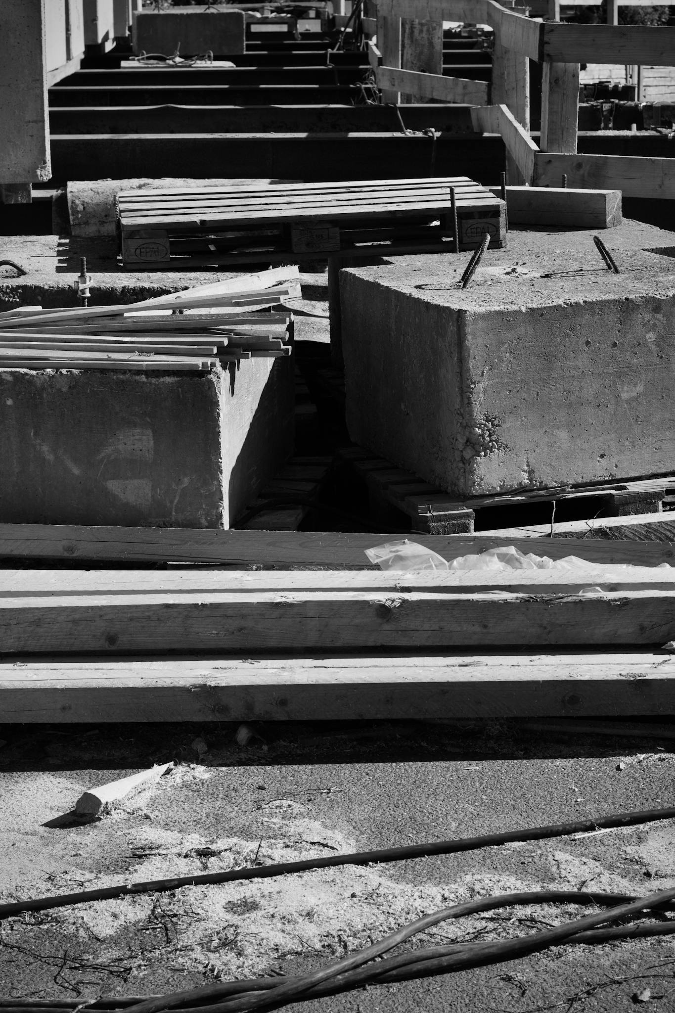 Monochrome view of construction materials including concrete blocks and wooden beams.
